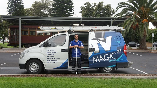 technician in front of his TV Magic van with  an antenna in front of him