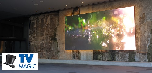 an outdoor large digital art display in a community setting with a TV Magic logo in bottom left corner