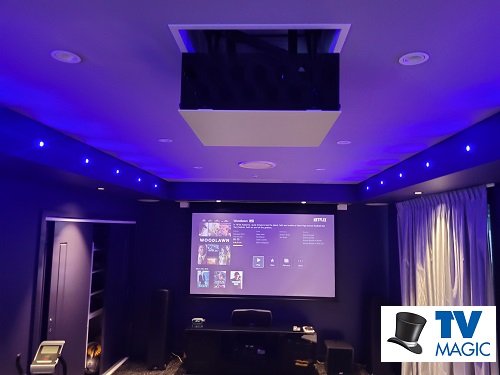 a motorised projector installed in-ceiling, with a TV Magic logo in bottom right corner