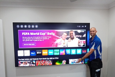 a technician standing next to a large wall mounted TV
