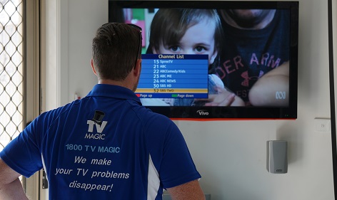 a technician fixing a clients TV reception. Image has a TV with a settings menu displayed on the screen