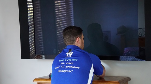 a technician attending to the finishing touches of a TV installation - wall mounted TV