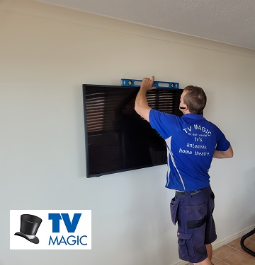 a technician mounting a TV on a wall