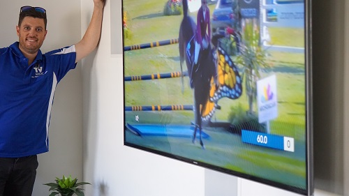 a technician standing next to a freshly wall mounted TV with built in surround sound