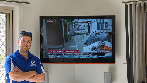 a wall mounted TV with a TV Magic technician in front of it