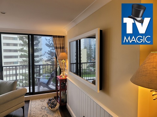 a mirror TV mounted on a wall in a living room with a TV Magic logo in top right corner