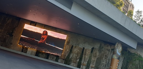 a large TV display in an outdoor area in a public setting, used as an art display