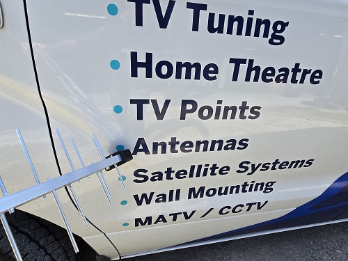Technician using an antenna mast to point to antenna services on side of van