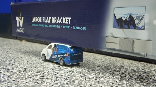 Close up of a TV Magic TV wall bracket with a mini TV Magic van in front of it.