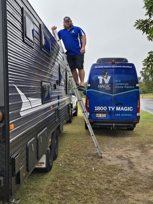 Technician on a ladder on the side of a customers caravan