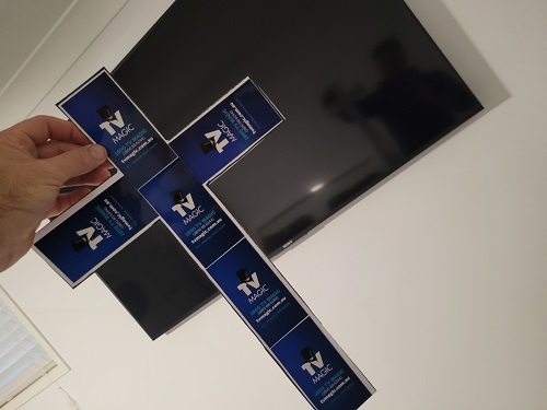 Cross made from TV Magic stickers, in front of big TV