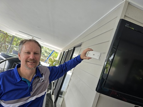 Technician holding a TV points up to a wall ready for installation