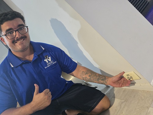 Technician holding a TV point to a wall.