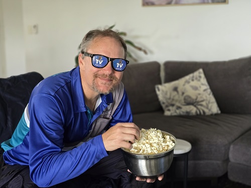 Technician lounging eating popcorn, wearing TV Magic sunglasses