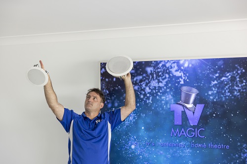 Technician holding up some speakers in front of a large screen