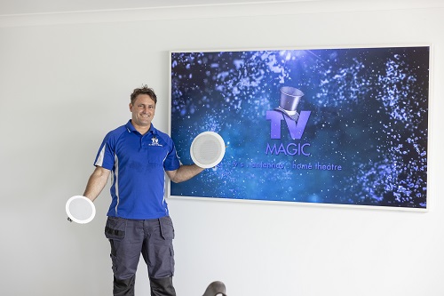 Technician holding speakers in front of a wall mounted large screen