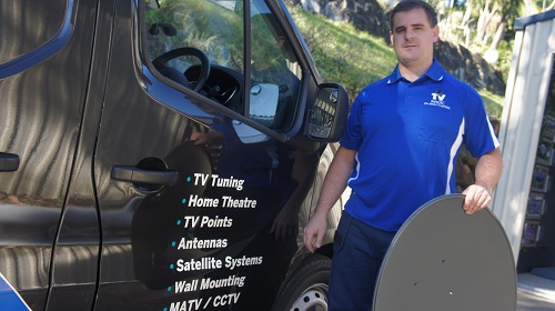 Technician holding a satellite dish next to his TV Magic van.