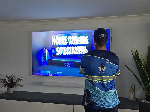 Technician Mitch facing a TV and soundbar installation he completed.