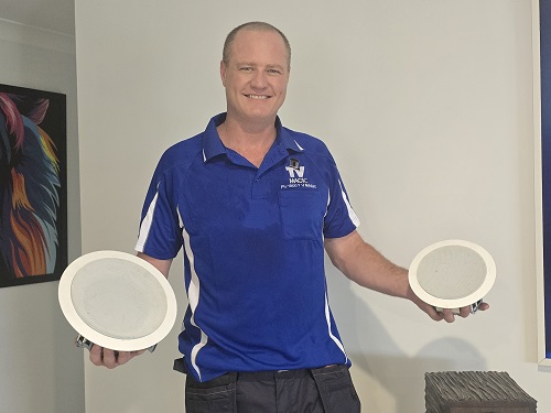 Technician with speakers in hand, ready for installation.