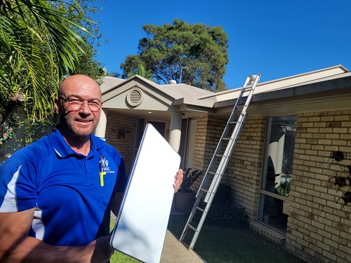 Technician holding a Starlink dish ready for installation.