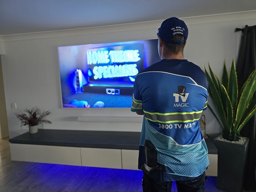 Mitch facing a TV and soundbar system he installed.