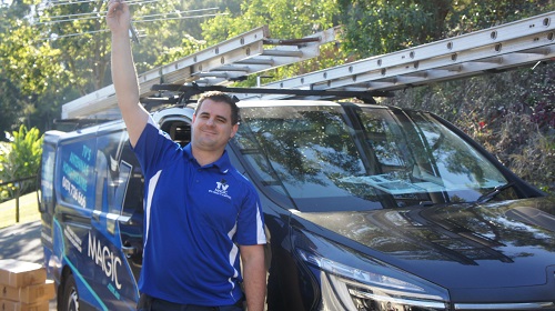 Technician holding up an antenna, standing next to his van