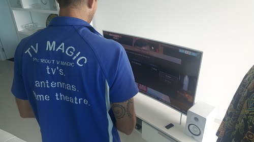 Technician facing a TV he is setting up