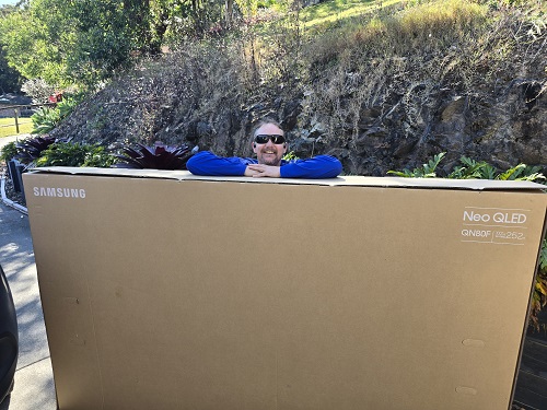 Technician with a large boxed TV ready for transportation