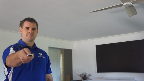 Technician holding a remote next to a TV