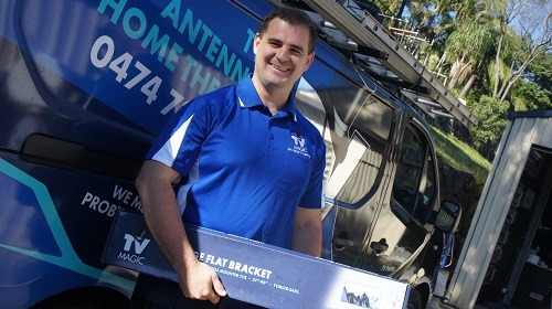 Technician holding a wall bracket, standing next to his van