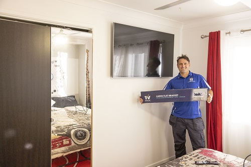 Technician holding a wall bracket, next to a TV