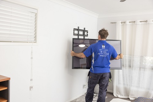 Technician holding a TV ready to mount on the wall