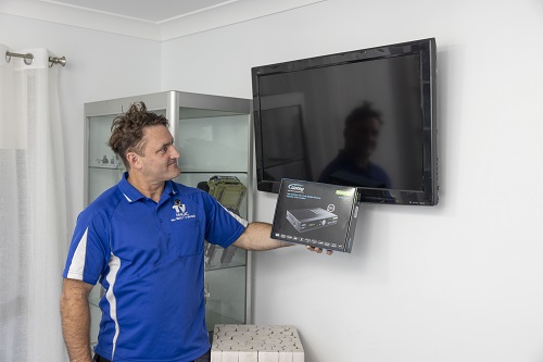 Technician holding a vast box in front of a TV