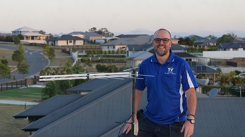 Technician next to an antenna installation he completed.