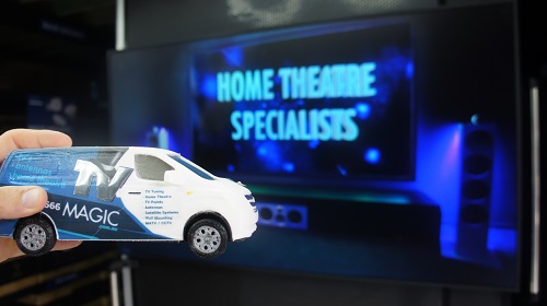 Big screen with caption "Home Theatre Specialists" and mini TV Magic van in front of it