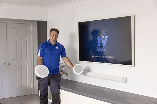 Technician holding up 2 speakers in client living area