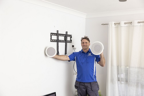 Technician holding up speakers ready to install post TV installation