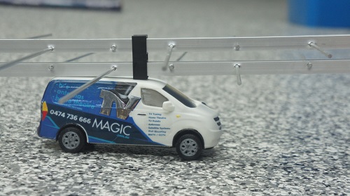 Close up of an antenna with a mini TV Magic van in front of it.