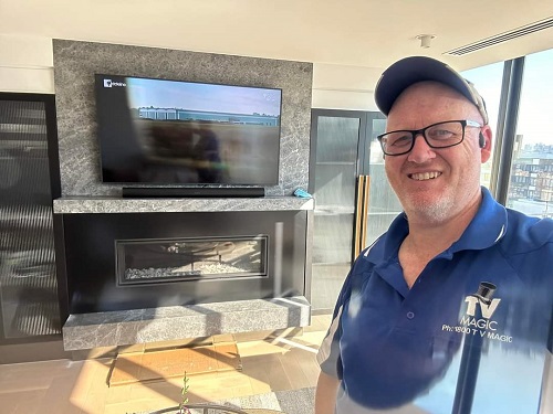 Technician in front of a large TV he just wall mounted