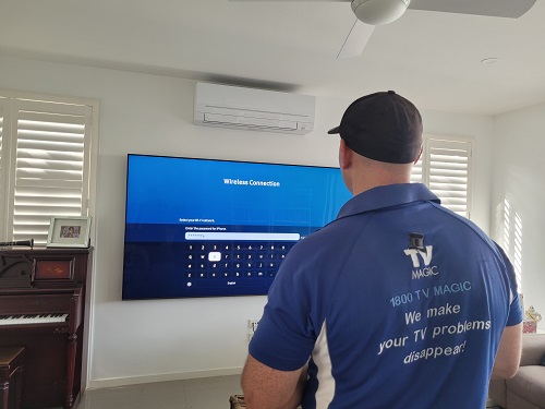 Technician - Brendan, facing a TV he is setting up.
