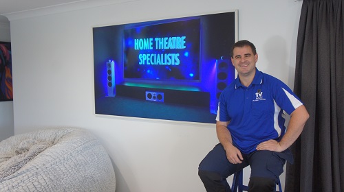 Technician sitting in front of a TV he just installed.