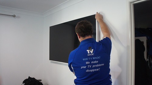 Technician wall mounting a TV