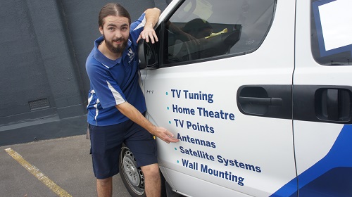 Technician pointing to services on the side of his TV Magic van