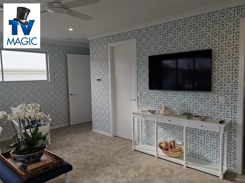 A wall mounted TV by TV Magic. TV Magic logo in top left corner
