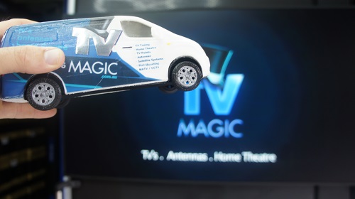 A large TV with TV Magic logo on screen. Mini TV Magic van held up in front of it.