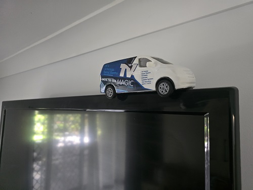 Close up of a mini TV Magic van on top of a wall mounted TV