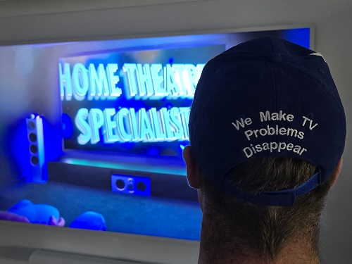 TV with caption "home theatre specialists" Technician with back of hat showing.