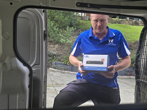 Technician holding a vast decoder box in the doorway of his van.