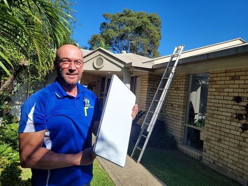 Technician holding a Starlink dish ready for installation.