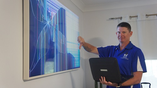 Technician with a broken TV - giving it the thumbs down.